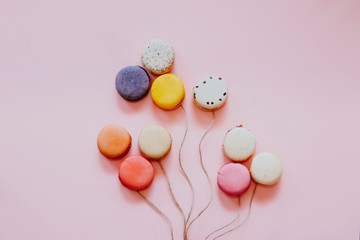 Fototapeta na wymiar French colorful macaroons cakes. Small sweet biscuits isolated on pink background. Dessert. Flat lay of macaroons in form of balloons. Happy bithday and valentine’s day creative minimal concept.
