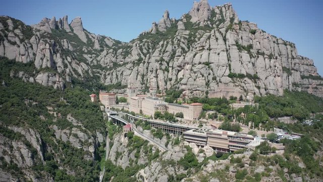 Drone shot of serrated mountain with Benedictine abbey, Barcelona, Catalonia, Spain. Famous Santa Maria de Montserrat monastery located on rocky range and notable for image of Virgin of Montserrat