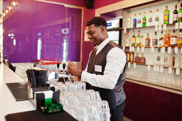 African american bartender at bar pouring from tap fresh beer into the glass in pub.