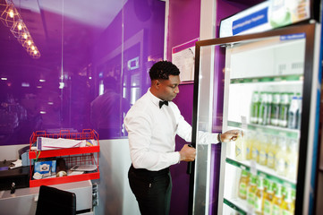 Fototapeta premium African american bartender at bar taking beer from fridge.