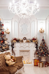 Fireplace in baroque style between Christmas trees decorated with red ornaments
