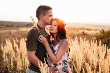 The guy kisses the girl, the sun in her hair, a photo in warm colors