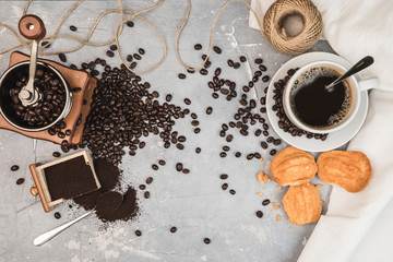 Coffee cup, with coffee grinder and coffee beans with ground powder on table. Top view Hot coffee and pastries on a old kitchen table. background concept Coffee cup and coffee grinder.