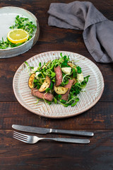 Green salad with steak, aubergine, sunflower sprouds and feta chese in ceramic plate on wooden background