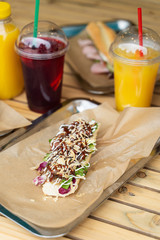 Open sandwich on a wheat bun with champignons, bacon, red cabbage and sauces with sweet drinks on a summer terrace