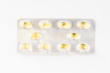 Ten yellow capsules packed in a blister pack isolated on white background