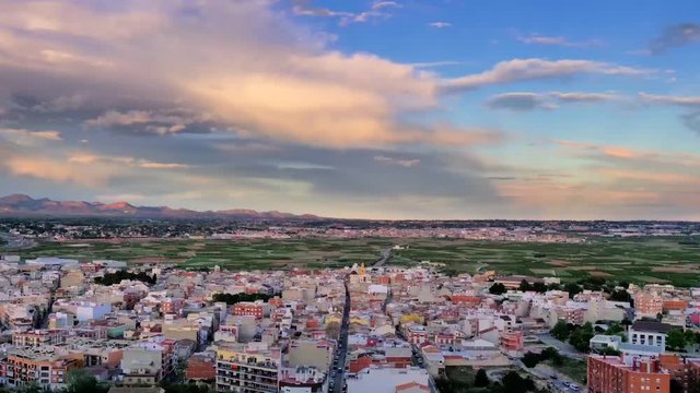 Time lapse de nubes de atardecer a gran velocidad sobre pueblo mediterraneo hasta el anochecer viendose las luces nocturnas de la calle