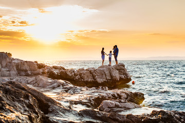 Young family look on the sea on sunset