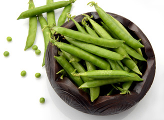 Fresh green peas in a bowl on white background