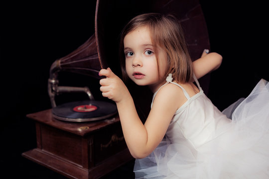 Foto de estudio de una ni&ntilde;a de 5 a&ntilde;os con un traje de ballet escuchando un antiguo gramofono