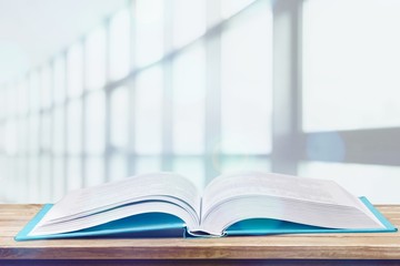 Stack of books with laptop on wooden table