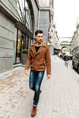 City style. Fashion. Man portrait. Handsome young man in casual clothes is walking in the city; full-length