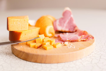 Ham, cheese and bread on a wooden cutting board. The breakfast in the village. Snack with beer or wine.