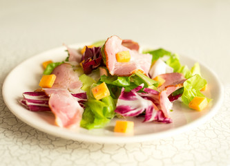 A plate of salad of green leaves, ham and cheese. Cutlery and a plate of fresh salad. Lunch. Intercontinental breakfast at the hotel.