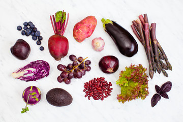 Raw purple vegetables and fruits over white marble
