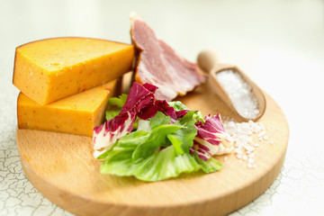 Fresh lettuce, cheese, ham and sea salt on a cutting board. Intercontinental breakfast at the hotel.