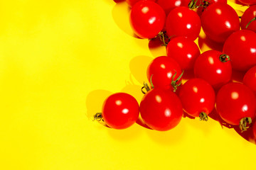 Red cherry tomatoes over yellow background. Colorful food background. Advertising, food ingredients concept.