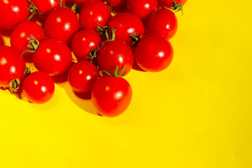 Red cherry tomatoes over yellow background. Colorful food background. Advertising, food ingredients concept.