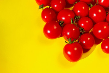Red cherry tomatoes over yellow background. Colorful food background. Advertising, food ingredients concept.