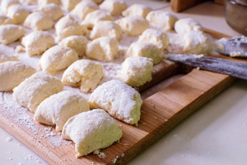 Sliced cottage cheese dough, sprinkled with flour, on board. Lazy dumplings, the national Ukrainian dish.