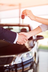 Young beautiful woman taking keys while sitting at car