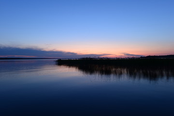 Fototapeta na wymiar Calm cloudless blue sky over the lake in the twilight glow in the night silence