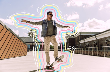people and leisure concept - smiling indian man doing trick on skateboard on roof top with glowing...