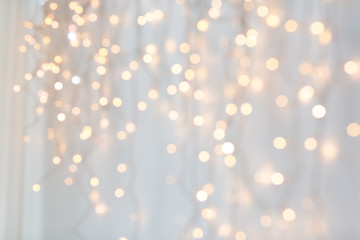 Fototapeta na wymiar holiday, illumination and decoration concept - bokeh of christmas garland lights over grey background
