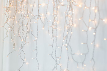 holiday, illumination and decoration concept - bokeh of christmas garland lights over grey...