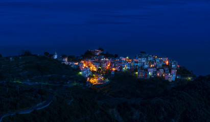 The fishing village of Corniglia in Cinque Terre, Italy, illuminated at night when the blue hour turns it into a fairytale 