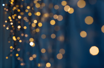 holiday, illumination and decoration concept - bokeh of christmas garland lights over dark blue background