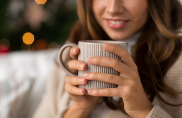 christmas, winter holidays and hygge concept - close up of happy woman with cup of coffee or tea at home