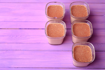 Five portions of chocolate milk dessert are on a wooden table of purple. Breakfast dessert on a violet wooden background. Flat lay.