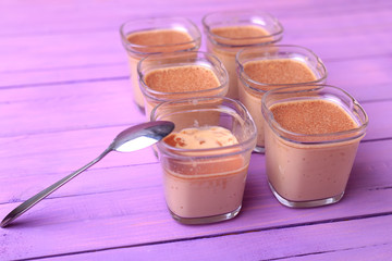 Six portions of chocolate milk dessert are on a wooden table of purple.