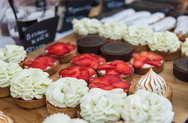 Background filled with colorful cakes and desserts with fresh fruits. Assorted different mini cakes with cream, chocolate and berries.