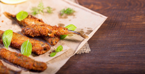 Fried anchovies in batter. Fried fish snack for beer. Mediterranean snack with greens and lemon.