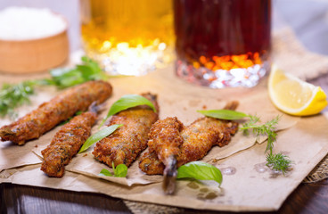 Fried anchovies in batter. Fried fish snack for beer. Mediterranean snack with greens and lemon.
