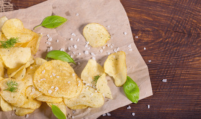 Potato chips with salt and greens on a table in a pub on a background of beer. Chips with greens as a snack to beer. October Beer Fest.