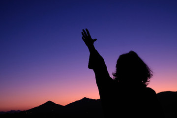 Naklejka premium Silhouette of woman stretching her arm over sunset