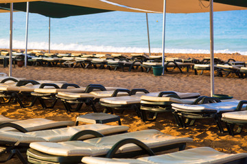 Fototapeta na wymiar Empty deck chairs for relaxing by the sea. Sea beach many empty sunbeds for leisure travelers