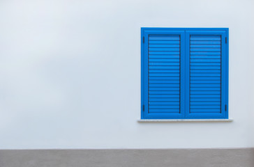 Quarantine in Europe, stay home.. Window with blue shutters on a white wall. Window with closed shutters. Blue window in the wall of the house.