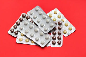 Set of pills blisters isolated on solid red background. Medical concept.  Potent drugs. White, brown and yellow pills.