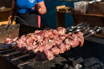 Delicious bbq grilling meat on open grill, outdoor kitchen. Food festival in city. tasty food roasting on skewers, food-court. Summer picnic.