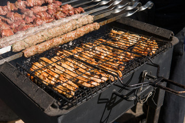 Delicious bbq grilling meat on open grill, outdoor kitchen. Food festival in city. tasty food roasting on skewers, food-court. Summer picnic.