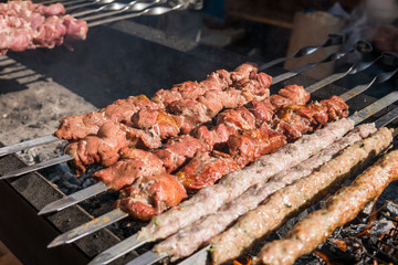 Delicious bbq grilling meat on open grill, outdoor kitchen. Food festival in city. tasty food roasting on skewers, food-court. Summer picnic.