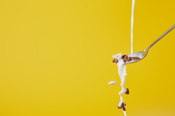 spoon with assorted cereal and milk splashes isolated on yellow