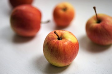 five apples, red with yellow spots, lie on a white table