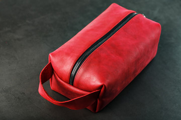 Naklejka premium Bag for cosmetics and jewelry made of genuine red leather, on a dark background. Handwork.