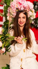 Young pretty girl holding flowers in their hands. Portrait of young woman in lilac wreath.