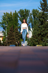 Fototapeta na wymiar Young beautiful brunette woman in jeans and white blouse walking in summer street
